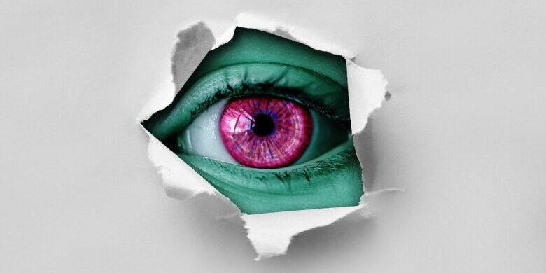 eye looking through torn paper